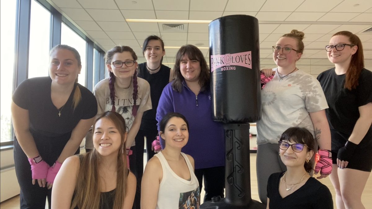 Members of Pink Gloves surrounding a punching bag.